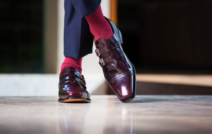 Fashionable man stands in leather buckle up shoes and red socks